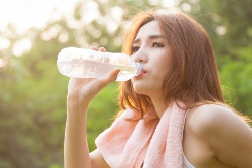 Woman sitting tired and drinking water after exercise.
